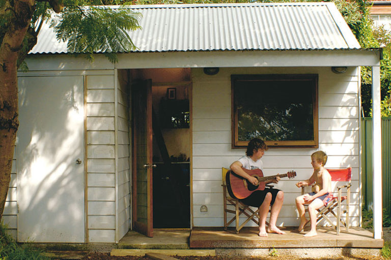 build a backyard cabin, two boys in front of an outdoor cabin