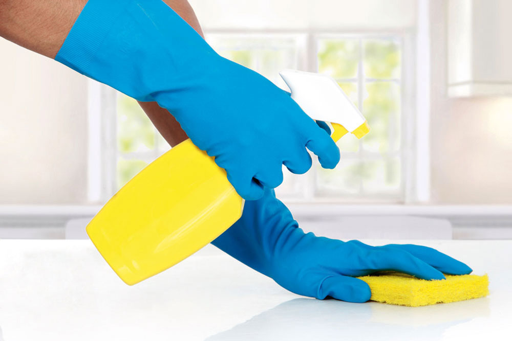 man wiping bench with blue gloves and a yellow sponge