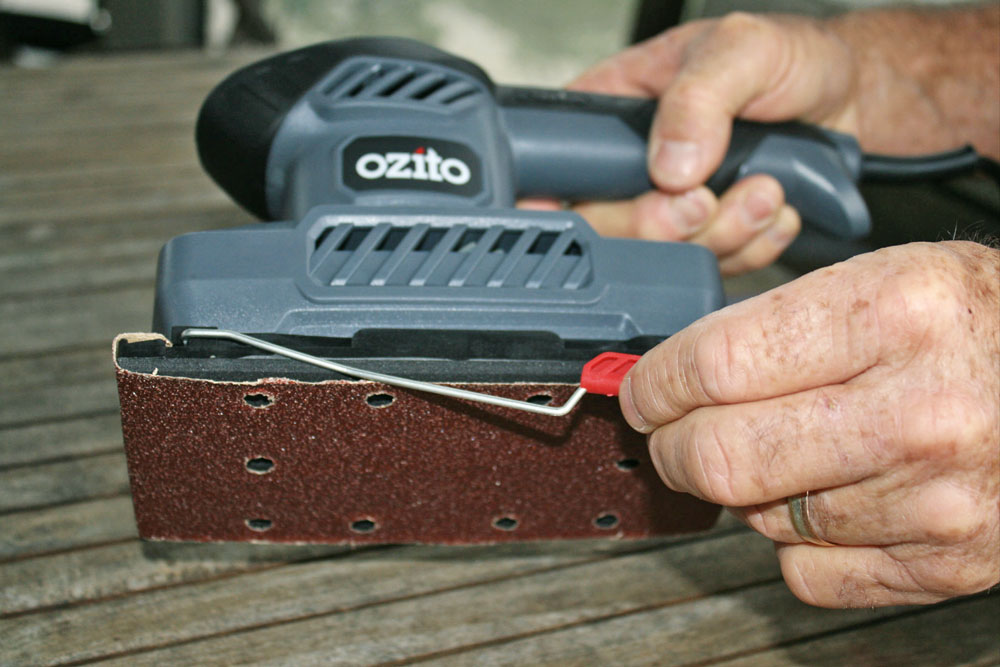 loading abrasive paper into an ozito orbital sander, handyman magazine, essential guide to sanding, 